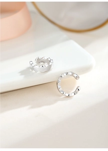Détail de manchette d'oreille argent S925 en forme de C avec bords ondulés sur plat céramique