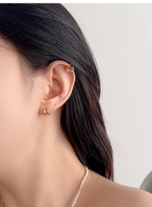 Close-up of minimalist gold curved ear cuff and pearl beaded necklace on model