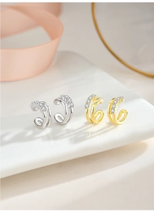 Detail of silver and gold double-layered C-shaped ear cuffs with sparkling zirconia stones