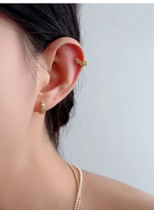 Détail d'un ensemble de bagues d'oreille et créoles dorées serties de zircons