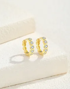Macro shot of gold-plated S925 silver huggie earrings with five round-cut zircons