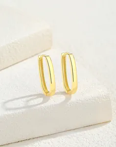 Macro shot of gold-plated S925 sterling silver U-shaped oval earrings on white stone