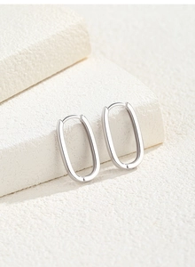 Detailed close-up of polished S925 sterling silver U-shaped hoop earrings on white stone