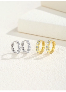 Detail of silver and gold hoops featuring micro-set round cubic zirconia on stone base