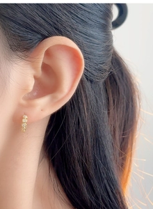 Detailed close-up of gold Huggie hoop earring with four micro-set round zircons