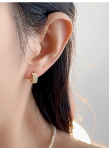 Close-up of gold-plated hoop earrings featuring three rows of micro-paved sparkling cubic zirconia