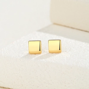 Minimalist square sugar cube stud earrings in polished gold finish on stone display