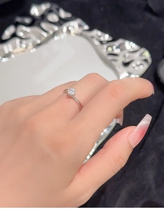 Close-up of a silver four-prong moissanite ring worn on a finger for a luxury look