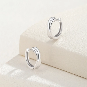 Minimalist S925 sterling silver crossover hoop earrings on a white stone pedestal