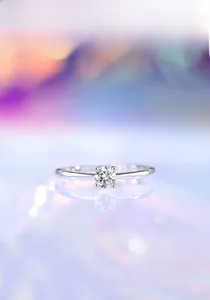Macro view of polished silver four-prong ring with a brilliant round moissanite stone