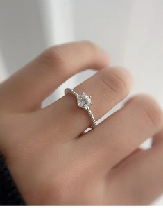Macro shot of 5mm moissanite ring with beaded silver band and classic claw setting