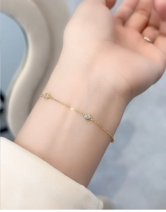 Close-up of minimalist gold S925 sterling silver bracelet with round bezel-set zircon stones