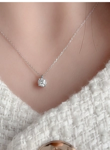 Close-up of 5mm moissanite solitaire pendant on 925 silver chain worn by model