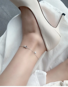 Detail of S925 sterling silver anklet featuring heart and bow charms on model ankle