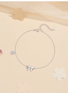 Detailed macro view of S925 sterling silver anklet with bow and zircon heart charms
