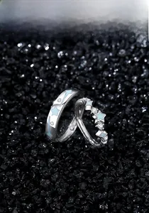 Detailed view of S925 silver couple rings with blue stars on dark pebble background