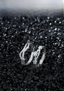 Detailed macro view of S925 silver couple rings featuring textured branch patterns and blue flowers