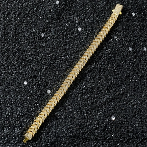 Bracelet hip-hop doré serti de strass sur fond de pierres noires, vue détaillée