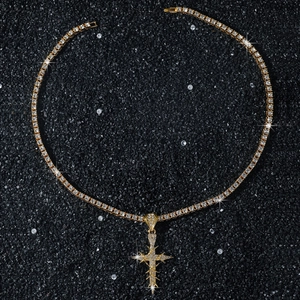 Detail of gold tennis chain and thorn wrapped cross pendant with sparkling stones