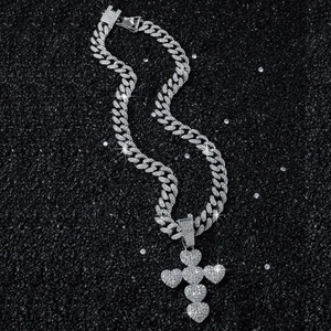 Silver iced-out cuban chain necklace with a sparkling heart cross pendant on black sand