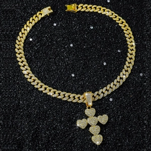 Macro shot of gold hip hop Cuban chain with iced out heart cross pendant on black surface