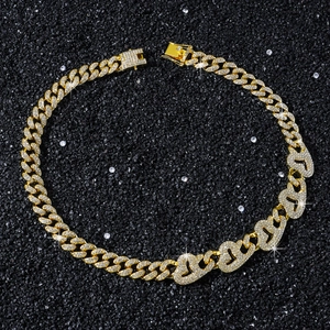 Dettaglio della collana a maglie cubane dorate con cuori glitterati su sfondo di sabbia nera