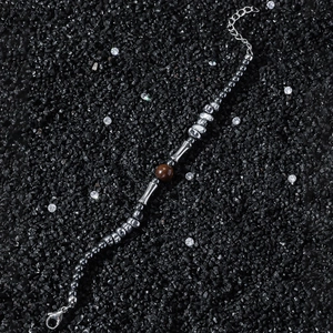 Tiger eye stone bracelet with silver beads and metal tube elements on a dark stone background