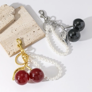 Handmade cherry resin keychain with faux pearls and metal clips on a white background