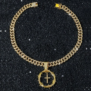 Gros plan détaillé sur la chaîne cubaine dorée et le pendentif croix ronde avec cristaux blancs