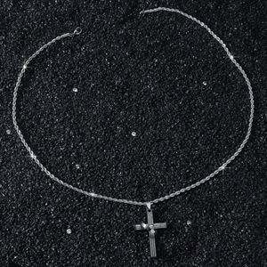 Détail du pendentif croix en acier inoxydable avec le texte gravé du Notre Père en espagnol