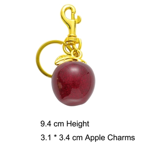 Détail d'un porte-clés pomme rouge pailleté avec fermoir doré et dimensions du produit