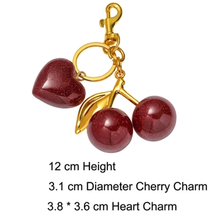 Macro shot of dark red glitter resin cherry and heart charms with golden keychain hooks