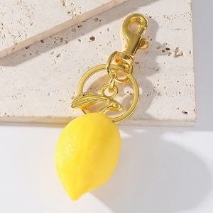 Detailed close-up of a resin lemon keychain with gold metal rabbit charm and texture