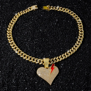 Macro shot of hip hop iced out broken heart pendant with lightning bolt on gold cuban chain