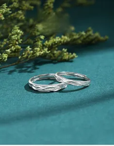 Macro detail of S925 sterling silver couple rings with natural wood grain texture