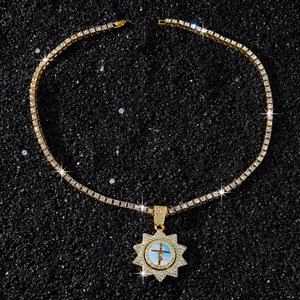 Vue détaillée de la chaîne tennis dorée et du pendentif croix tournante avec cristaux