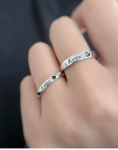 Close-up of S925 silver couple rings featuring Love engraving and heart cutout detail