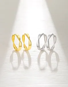Detail of twisted S925 silver hoop earrings in gold and silver finish with light shadow