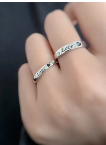 Close-up of S925 sterling silver couple rings with LOVE engraving and black heart