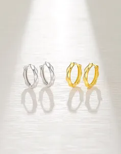 Vue macro de boucles d'oreilles créoles S925 en argent avec texture ondulée argent et doré