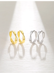 Macro detail of twisted 925 silver hoop earrings in polished gold and silver finishes