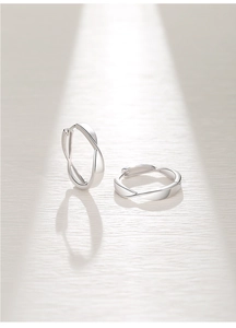 Macro detail of silver Mobius hoop earrings with polished twisted design on paper