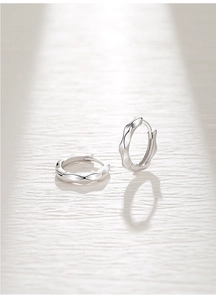 Vue détaillée de la texture ondulée irrégulière de ces boucles d'oreilles créoles en argent