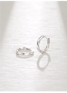Macro detail of silver Mobius hoop earrings with twisted wave texture and polished finish