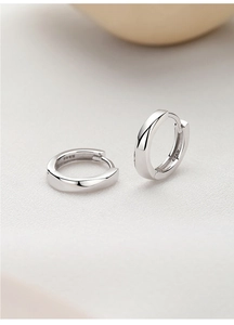 Macro shot of minimalist S925 sterling silver hoop earrings with twisted metal texture