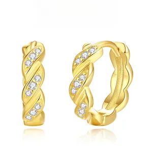 Nahaufnahme goldene gedrehte Creolen mit Mikro-Diamanten und glänzender Oberfläche