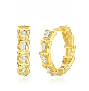 Macro detail of gold-plated snake-scale earrings with trapezoidal zircon inlay