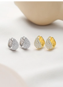 Macro view of silver and gold teardrop earrings with S925 hallmark and pave set zircons