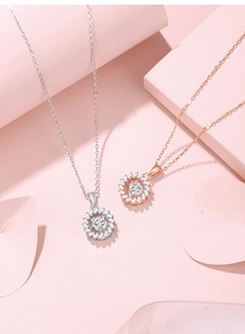 Detail of silver and rose gold sunflower necklaces on elegant pink background