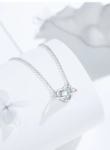 Macro shot of silver heart planet pendant necklace with moonstone and pavé details